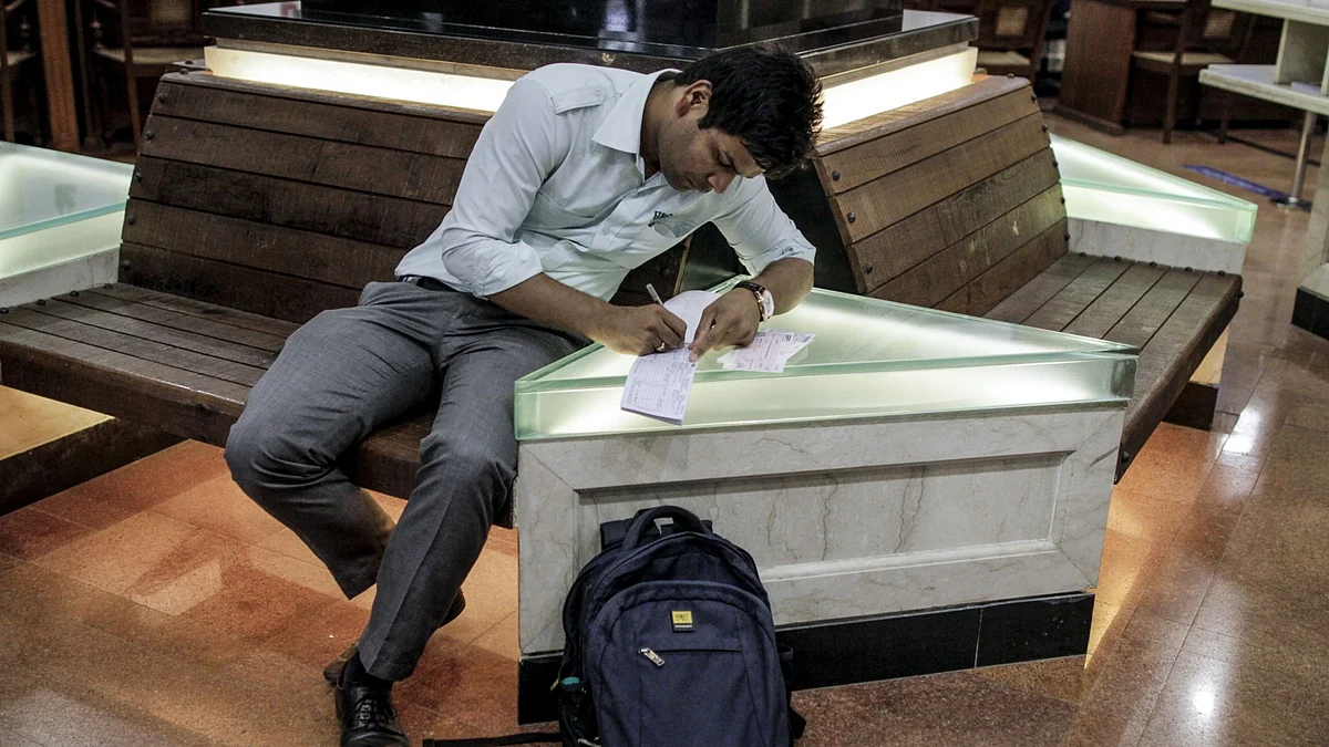 A customer writes on a cheque deposit slip at a bank branch in Mumbai. (Photographer: Dhiraj Singh/Bloomberg)