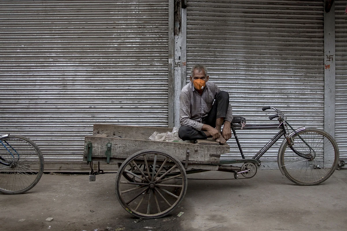 A day laborer sits on a tricycle outside a shuttered store in New Delhi, on Aug. 31, 2020. (Photographer: Anindito Mukherjee/Bloomberg)