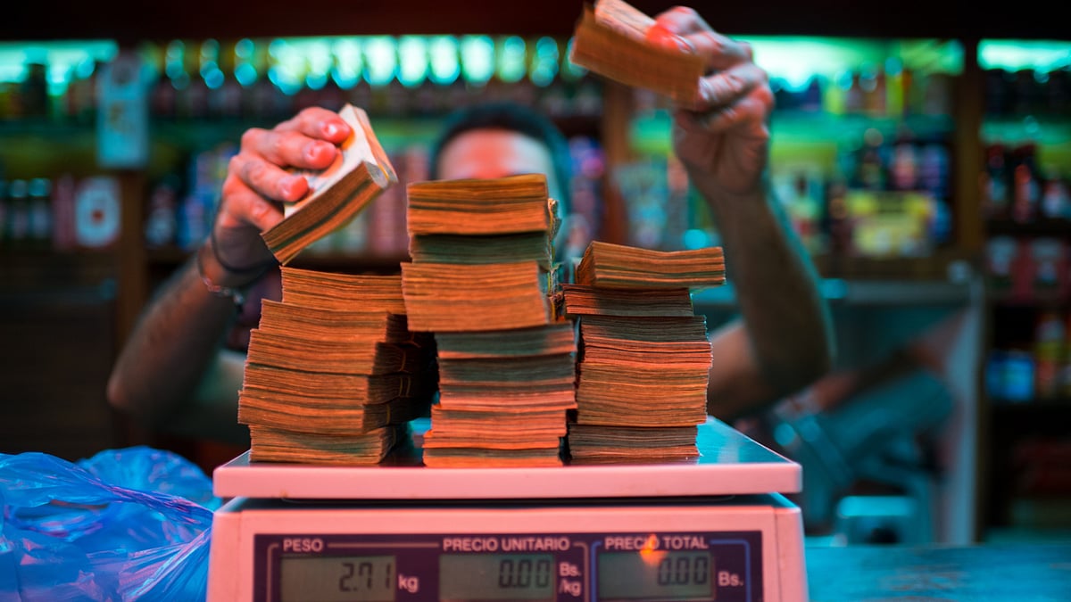 A manager weighs banknotes on a scale at a bakery in Venezuela. (Photographer: Manaure Quintero/Bloomberg)