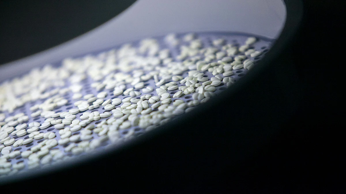 Tablets sit illuminated during the film-coating process in the laboratories (Photographer Krisztian Bocsi/Bloomberg)