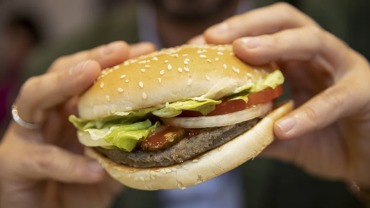 A customer eats a Rebel Whooper at a Burger King Holdings Inc. fast-food restaurant in Milan, Italy. (Photographer: Camilla Cerea/Bloomberg)