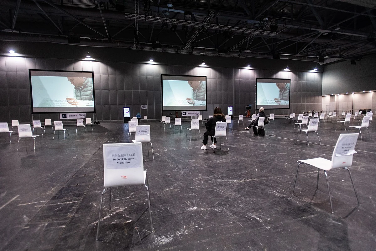 Travelers watch a saliva sample information video at a coronavirus testing facility at the AsiaWorld-Expo in Hong Kong on May 14. Photographer: Laurel Chor/Bloomberg 