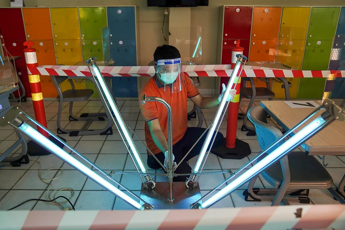 In West Java, Indonesia, a maintenance worker uses ultraviolet light to sanitize a classroom on July 24. Photographer: Dimas Ardian/Bloomberg 