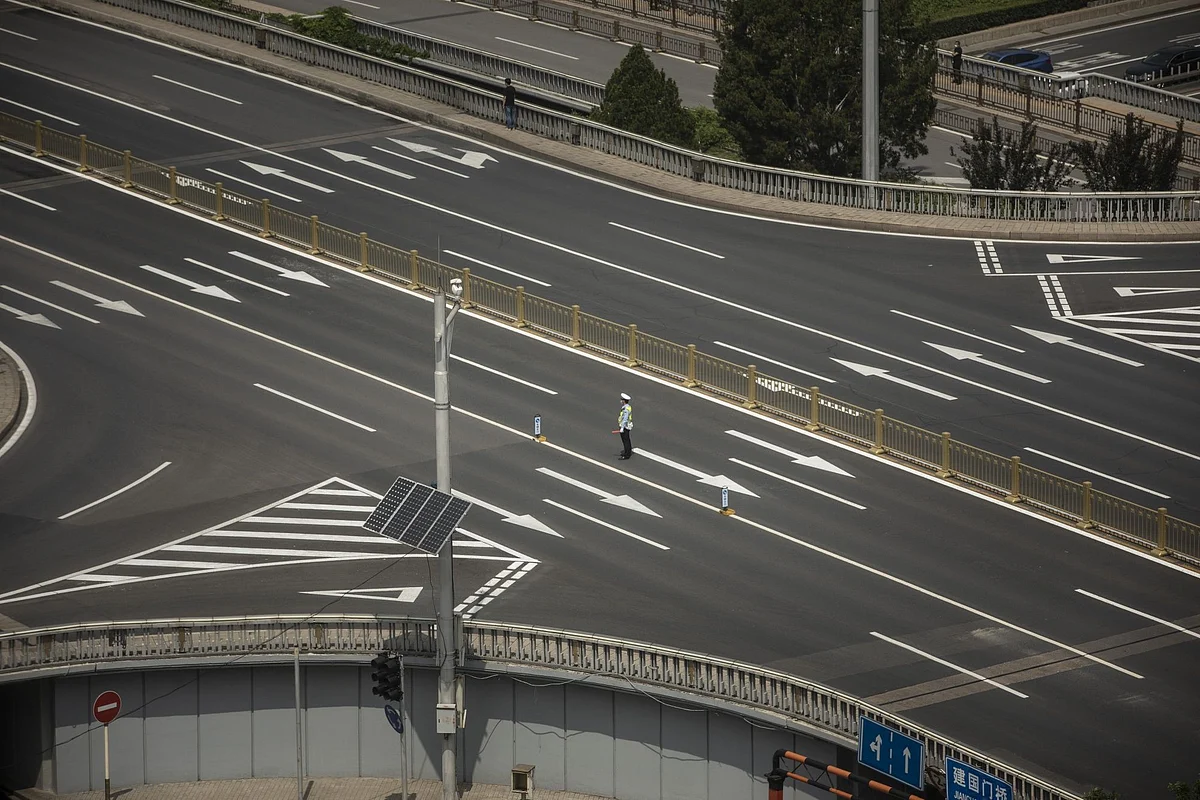 On a multilane road in Beijing on May 22, a traffic conductor had little to do. Photographer: Qilai Shen/Bloomberg 