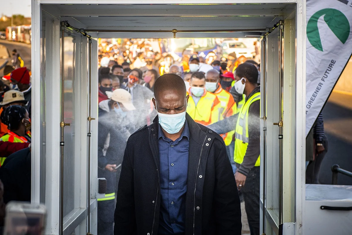 A commuter walks through a sanitization tunnel at the Rea-Vaya Thokoza Park bus station in Johannesburg on May 14. Photographer: Waldo Swiegers/Bloomberg 
