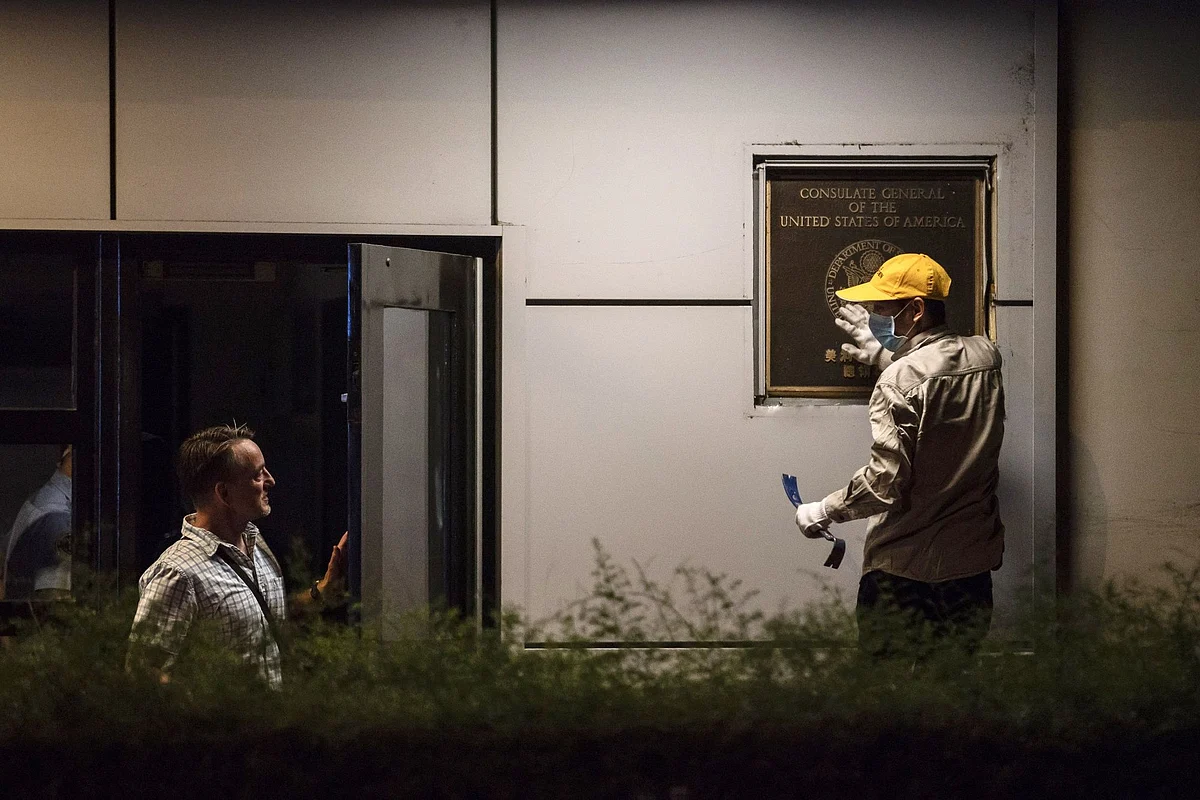 Jim Mullinax, U.S. consul general in Chengdu, speaks with a worker removing the consulate plate on July 26 after China ordered the building closed.Photographer: Qilai Shen/Bloomberg 