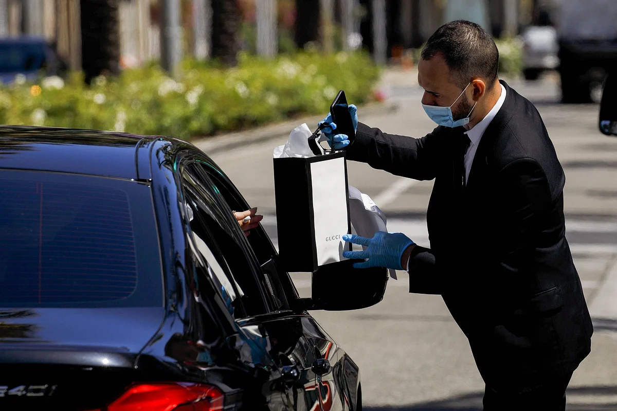 A Gucci employee delivers a purchase to a waiting customer at a pickup location on Rodeo Drive in Beverly Hills, California, on May 19. Photographer: Patrick T. Fallon/Bloomberg 