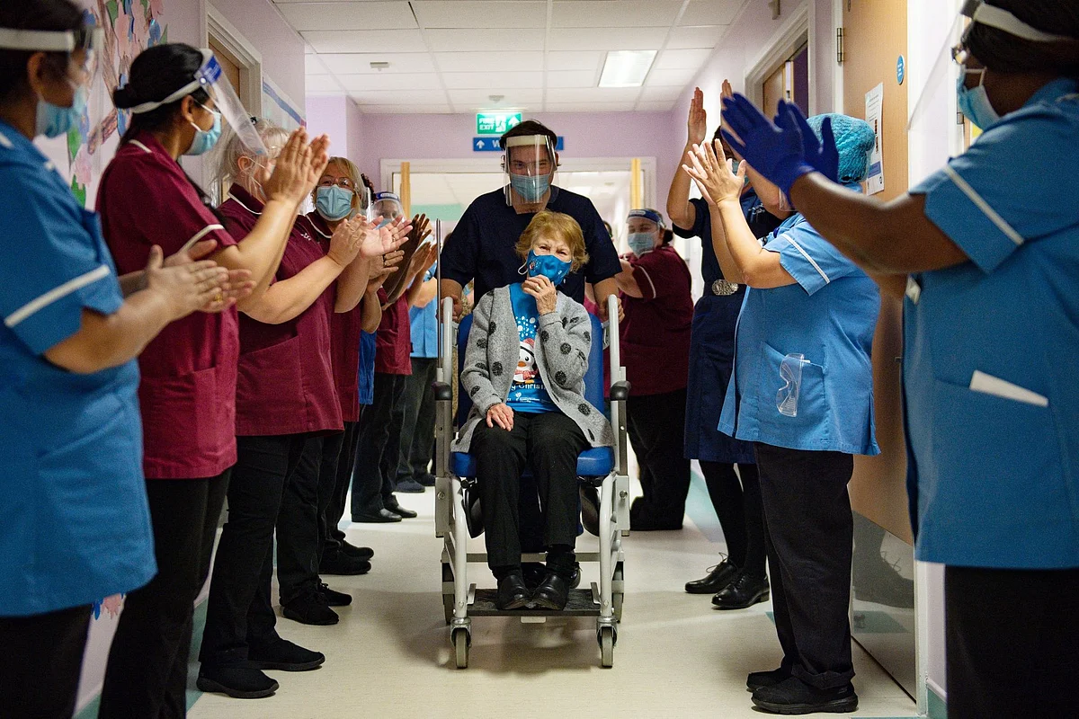 National Health Service staff in Coventry, England, applaud Margaret Keenan, 90, as she becomes the first person in the U.K. to get the Covid-19 vaccine on Dec. 8. Photographer: Jacob King/PA Wire/Bloomberg 