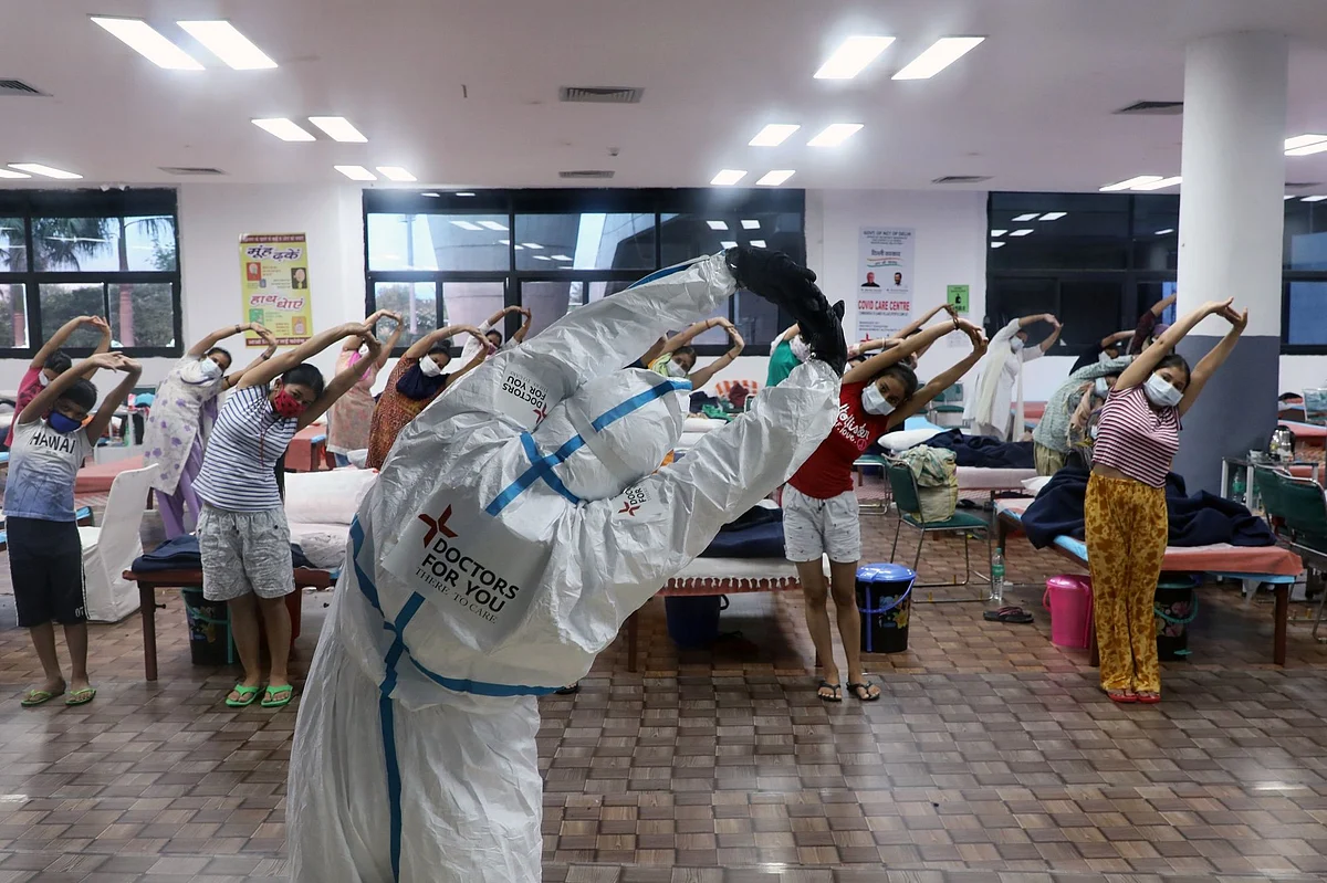 A health worker in full protective equipment conducts a yoga class for patients in a women’s ward of a Covid-19 center in New Delhi on July 30. Photographer. T. Narayan/Bloomberg