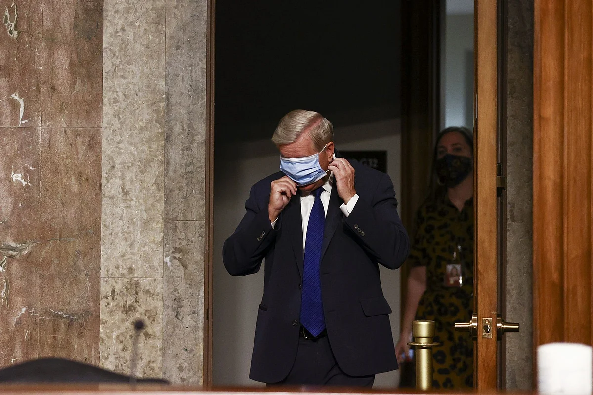 Republican Senator Lindsey Graham adjusts his mask at a hearing in Washington on Nov. 18. Photographer: Hannah McKay/Reuters/Bloomberg 