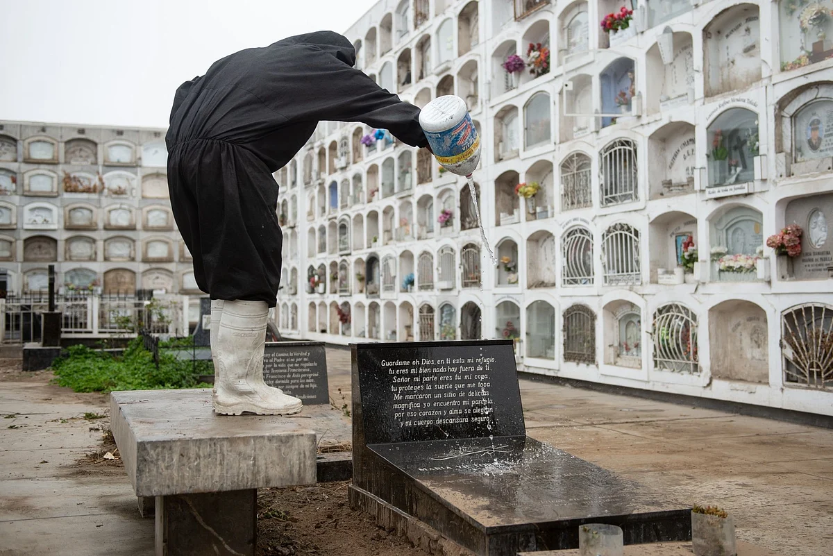 A worker pours bleach on the grave of a Covid-19 victim at the El Angel cemetery in Lima, Peru, on June 3. Photographer: Miguel Yovera/Bloomberg