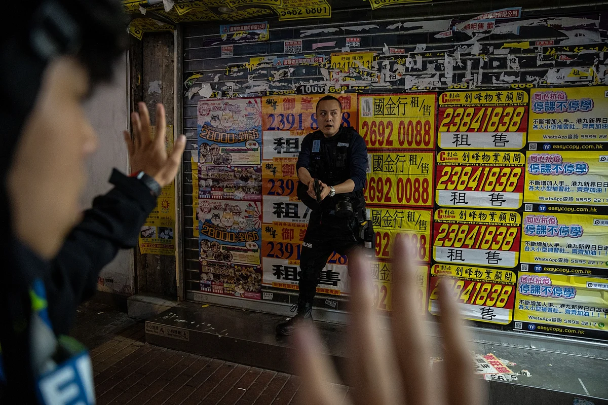A police officer draws his weapon during democracy protests in the Mong Kok district of Hong Kong on Feb. 29. Photographer: Roy Liu/Bloomberg