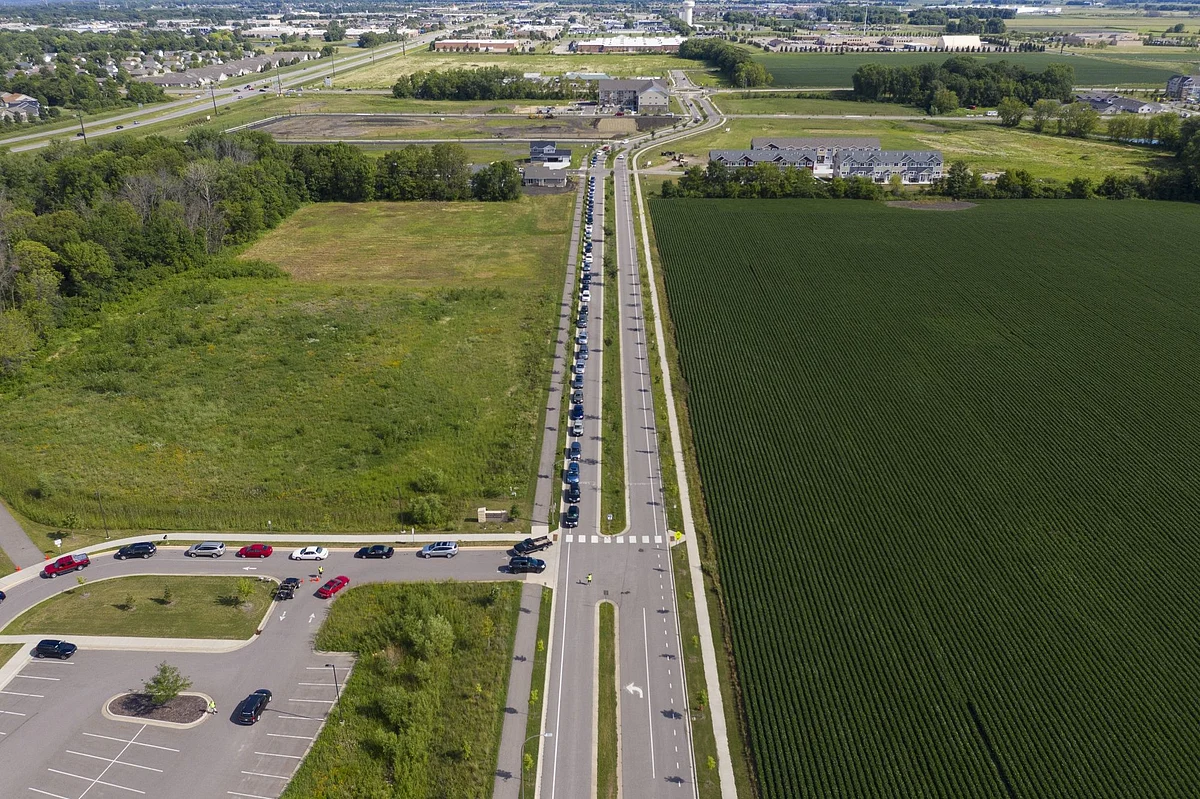Drivers line up alongside fields of crops at a charity food pantry in Mankato, Minnesota, on July 23. Photographer: Ben Brewer/Bloomberg 