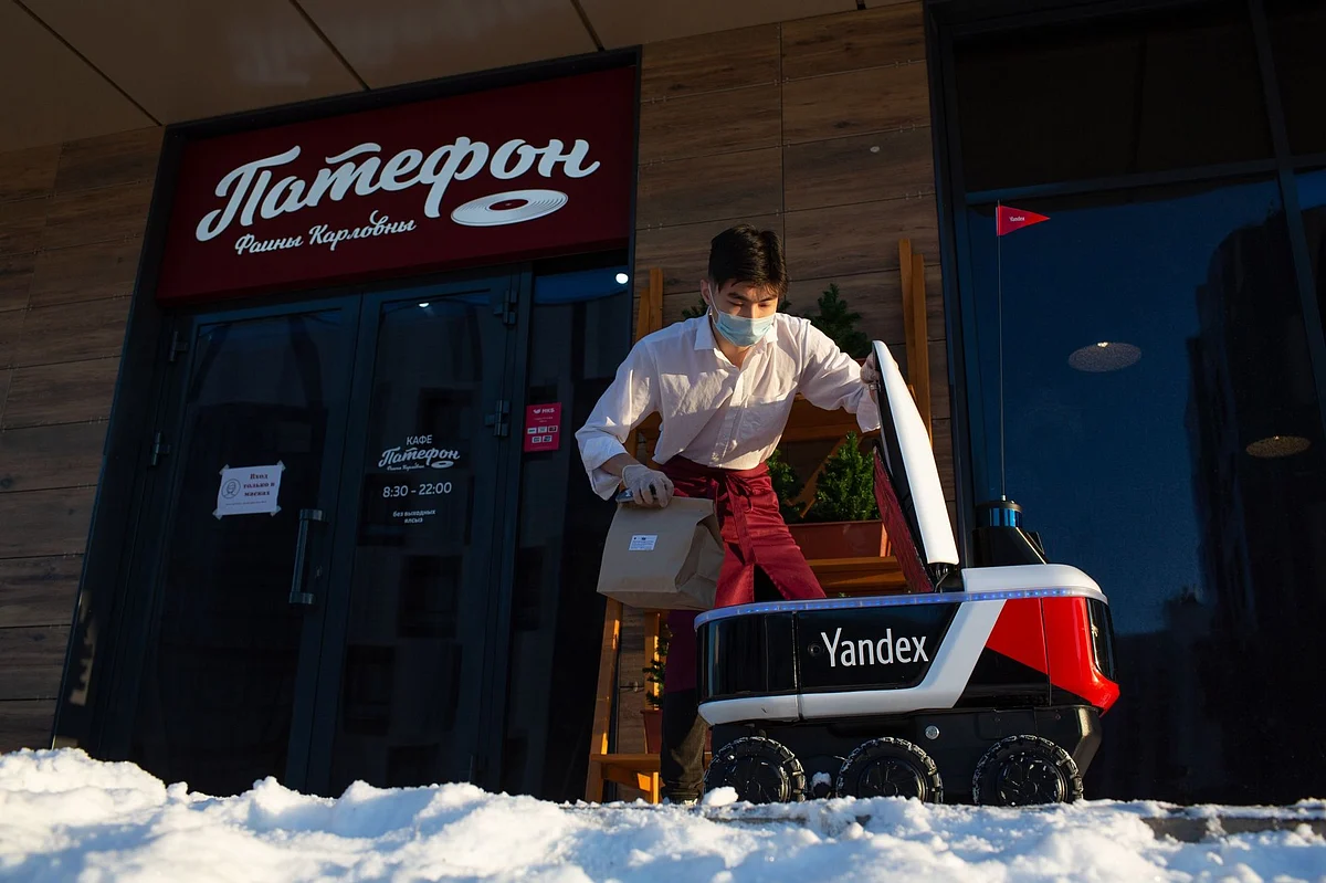 A restaurant worker places an order in an autonomous delivery robot in Innopolis, Russia, on Dec. 1. Photographer: Andrey Rudakov/Bloomberg 