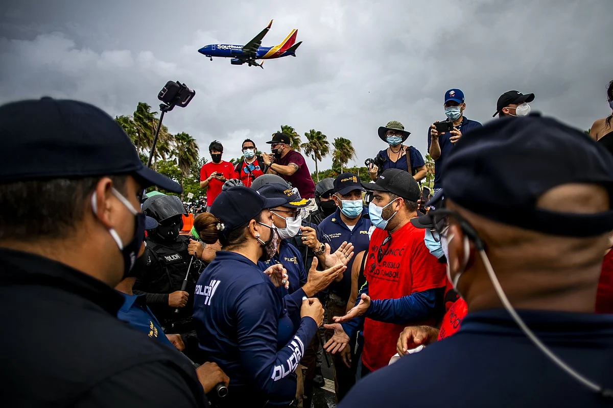 Police officers confront demonstrators in Puerto Rico during a protest against U.S. mainland tourists arriving from coronavirus hot zones on July 25. Photographer: Xavier Garcia/Bloomberg 