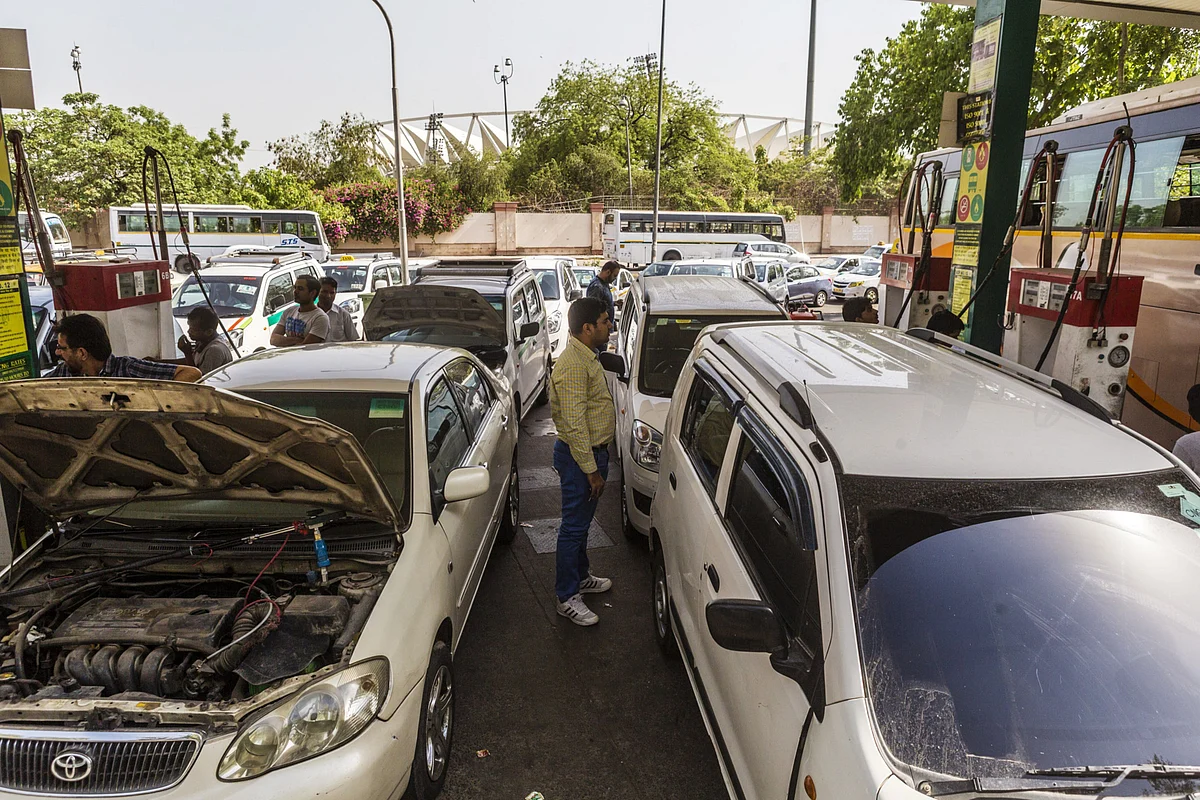 A man stands between vehicles being refueled with compressed natural gas (CNG) at an Indraprastha Gas Ltd. gas station in New Delhi. (Photographer: Prashanth Vishwanathan/Bloomberg)
