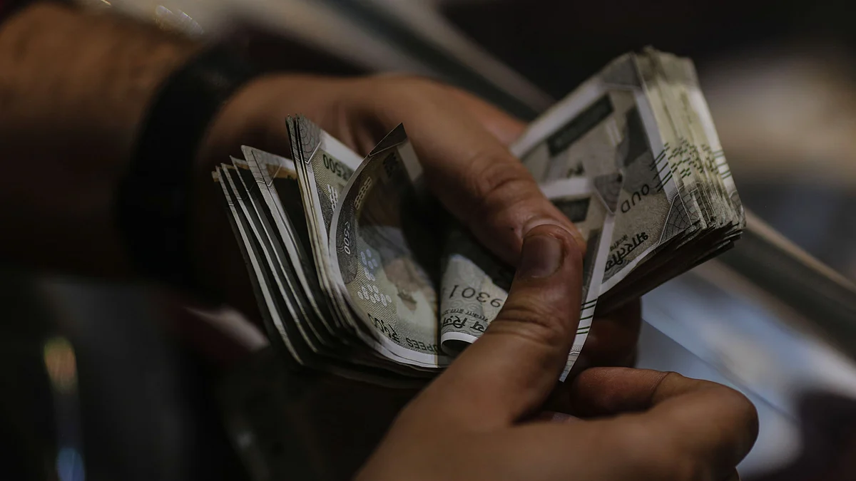 A customer counts Indian rupee banknotes at a jewellery store. (Photographer: Dhiraj Singh/Bloomberg)