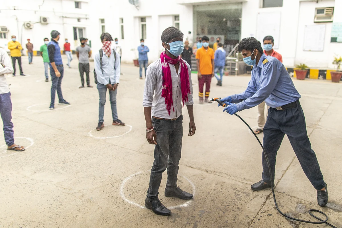 A security guard sprays a worker at a factory in Sonipat district, Haryana, on April 20, 2020. (Photographer: Prashanth Vishwanathan/Bloomberg)