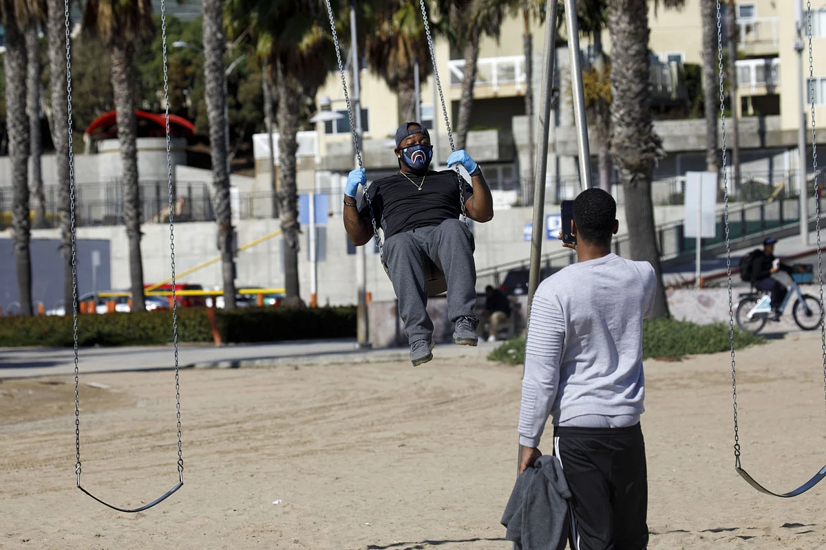 A person wearing gloves and a protective mask records a video for Instagram, in Santa Monica, California, on March 19, 2020. (Photographer: Patrick T. Fallon/Bloomberg)