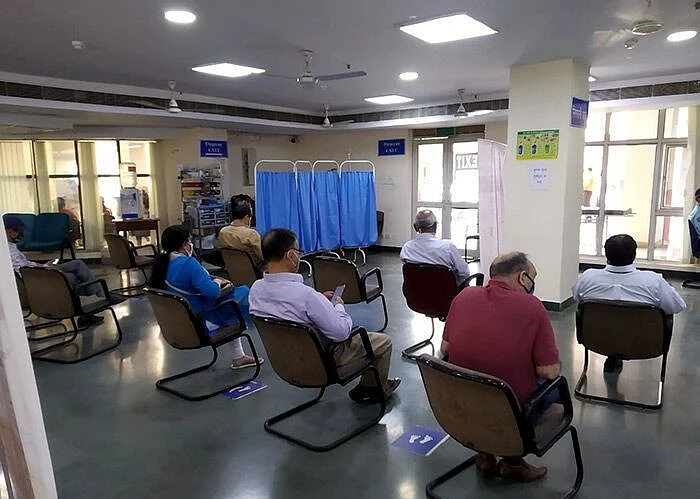People wait after taking their Covid-19 vaccination at Delhi’s Ram Manohar Lohia Hospital. Recipients are asked to wait 30 minutes after their shot to monitor for adverse reactions. (Photographer: Anoo Bhuyan/IndiaSpend)