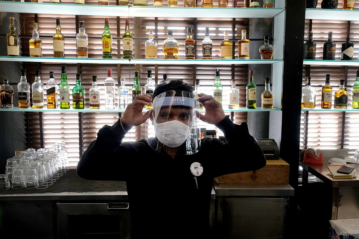 A bartender wearing a protective mask adjusts his face shield at a restaurant, in New Delhi, on Sept. 8, 2020. (Photographer: T. Narayan/Bloomberg)