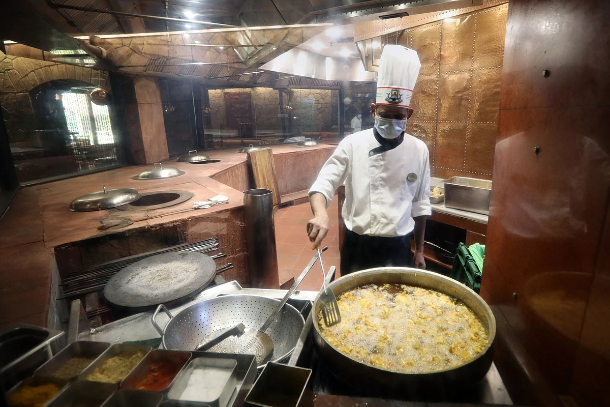 An employee wearing a protective mask cooks inside a restaurant in New Delhi, on Aug. 22, 2020. (Photographer: T. Narayan/Bloomberg)