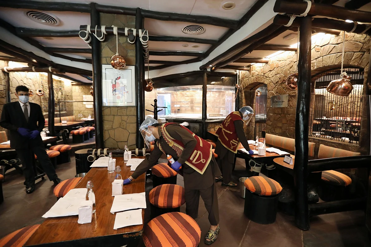 Employees wearing protective masks and face shields clean a restaurant in New Delhi, on Aug. 22, 2020. (Photographer: T. Narayan/Bloomberg)