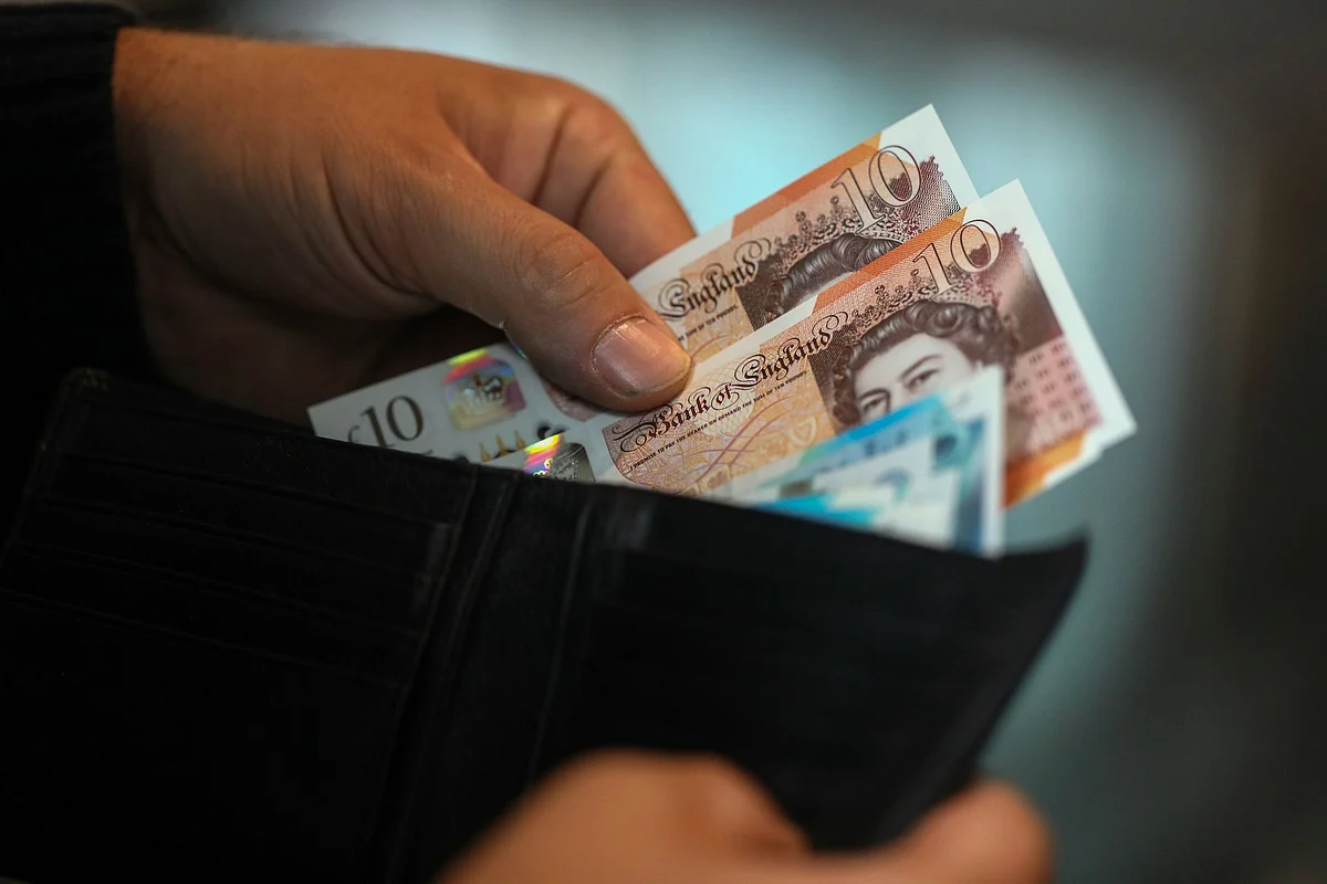 A man removes five and ten pound sterling banknotes from a wallet. Photographer: Chris Ratcliffe/Bloomberg