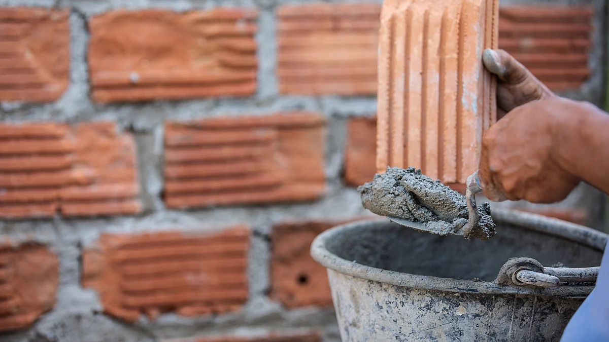 <div class="paragraphs"><p>A mason applying cement on bricks with trowel knife. (Source: freepik) </p></div>