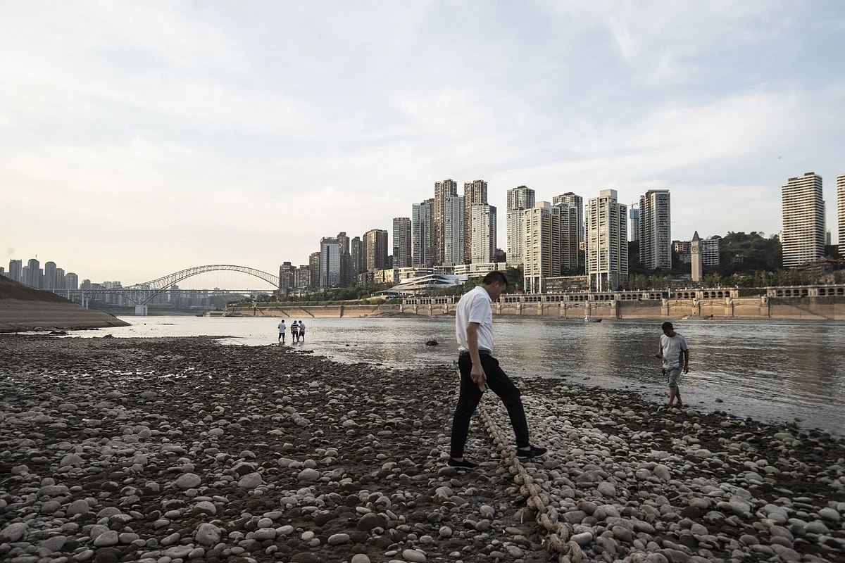 People stand near the shallow banks of the Jialing River in Chongqing, China, on Friday, Aug. 19, 2022. Photographer: Qilai Shen/Bloomberg