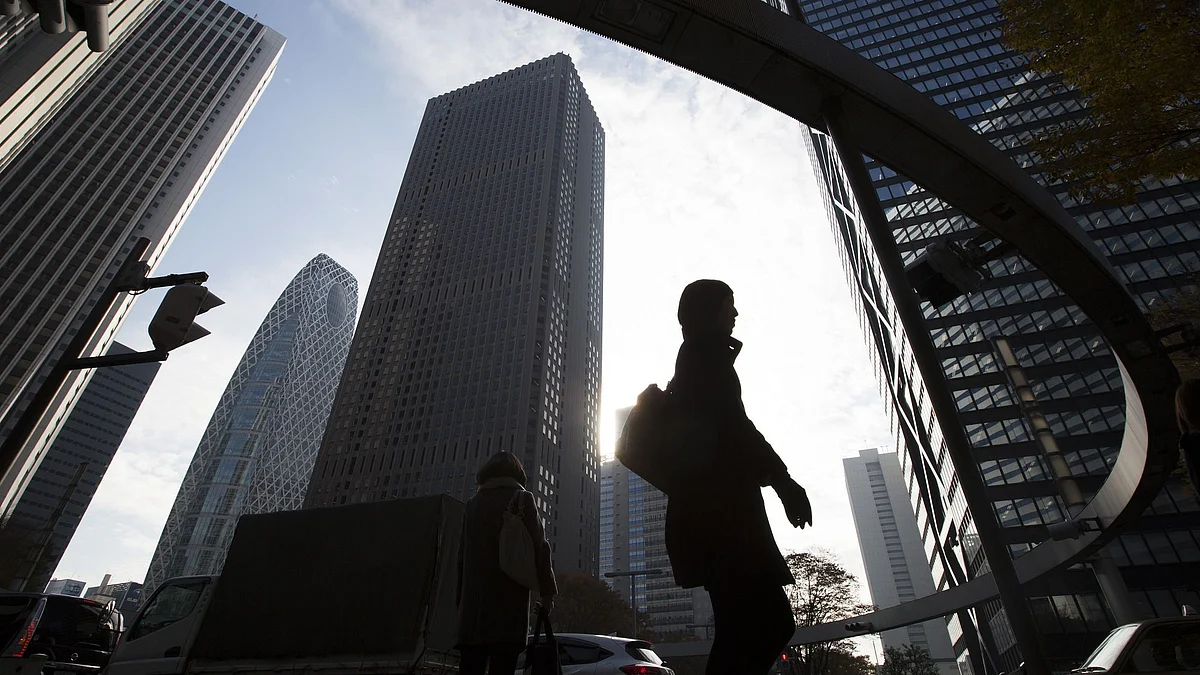 A morning commuter walks past buildings in Tokyo, Japan, on Thursday, Dec. 10, 2015. Photographer: Tomohiro Ohsumi/Bloomberg