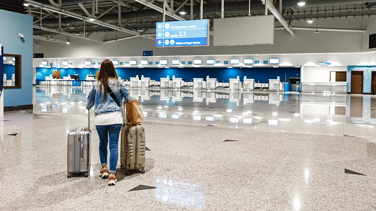 <div class="paragraphs"><p>A woman traveller walks along with suitcases at an airport. (Source: freepik)</p></div>