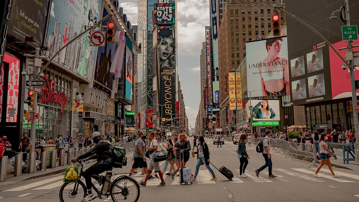 Pedestrians cross a street in the Times Square neighborhood of New York, U.S., on Saturday, Sept. 4, 2021. This month, as Broadway theaters, Lincoln Center, and other stages reopen, New Yorkers will see if the city's famous love for the arts has held strong enough to play a starring role in its economic revival.