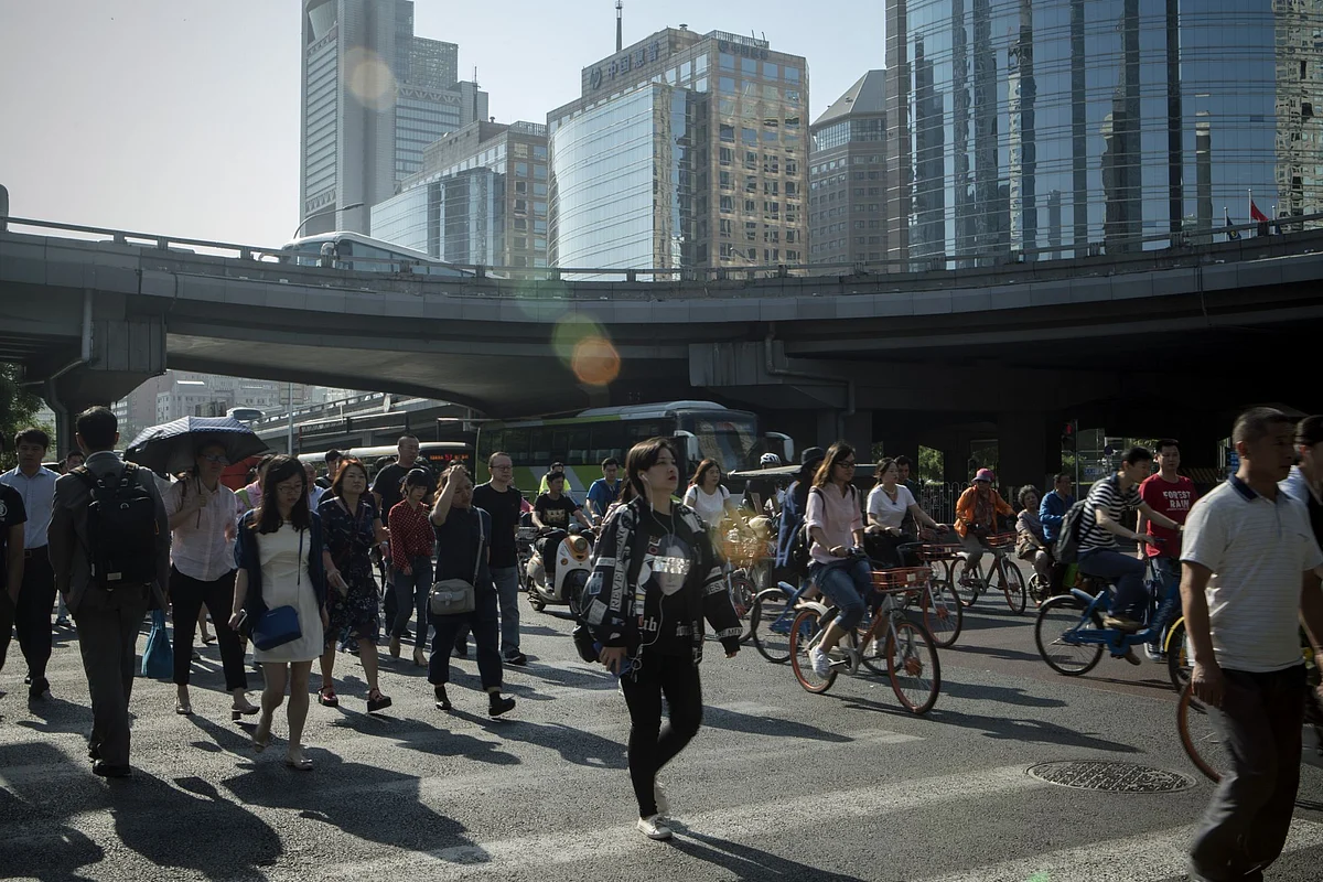 Pedestrians cross a road next to cyclists and other vehicles in the central business district in Beijing, China, on Friday, June 1, 2018. The People's Bank of China announced on Friday that it would add debt instruments tied to small-business and the green economy. Photographer: Giulia Marchi/Bloomberg