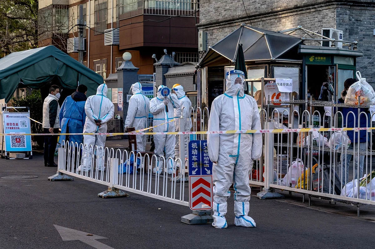 Workers in protective gear at a neighborhood placed under lockdown due to Covid-19 in Beijing, China, on Monday, Nov. 21, 2022. Surging infections are threatening to overwhelm some of the country’s biggest and most important cities, with local officials stymied over how to control the contagion without the usual tools of mass citywide testing and snap lockdowns.