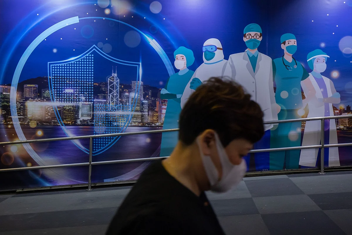 A pedestrian walks past an mural featuring healthcare workers in Hong Kong, China, on Friday, Feb. 18, 2022. Hong Kong is considering stricter social-distancing measures and preparing for a universal testing push to try to curtail an escalating virus outbreak thats straining its health infrastructure.