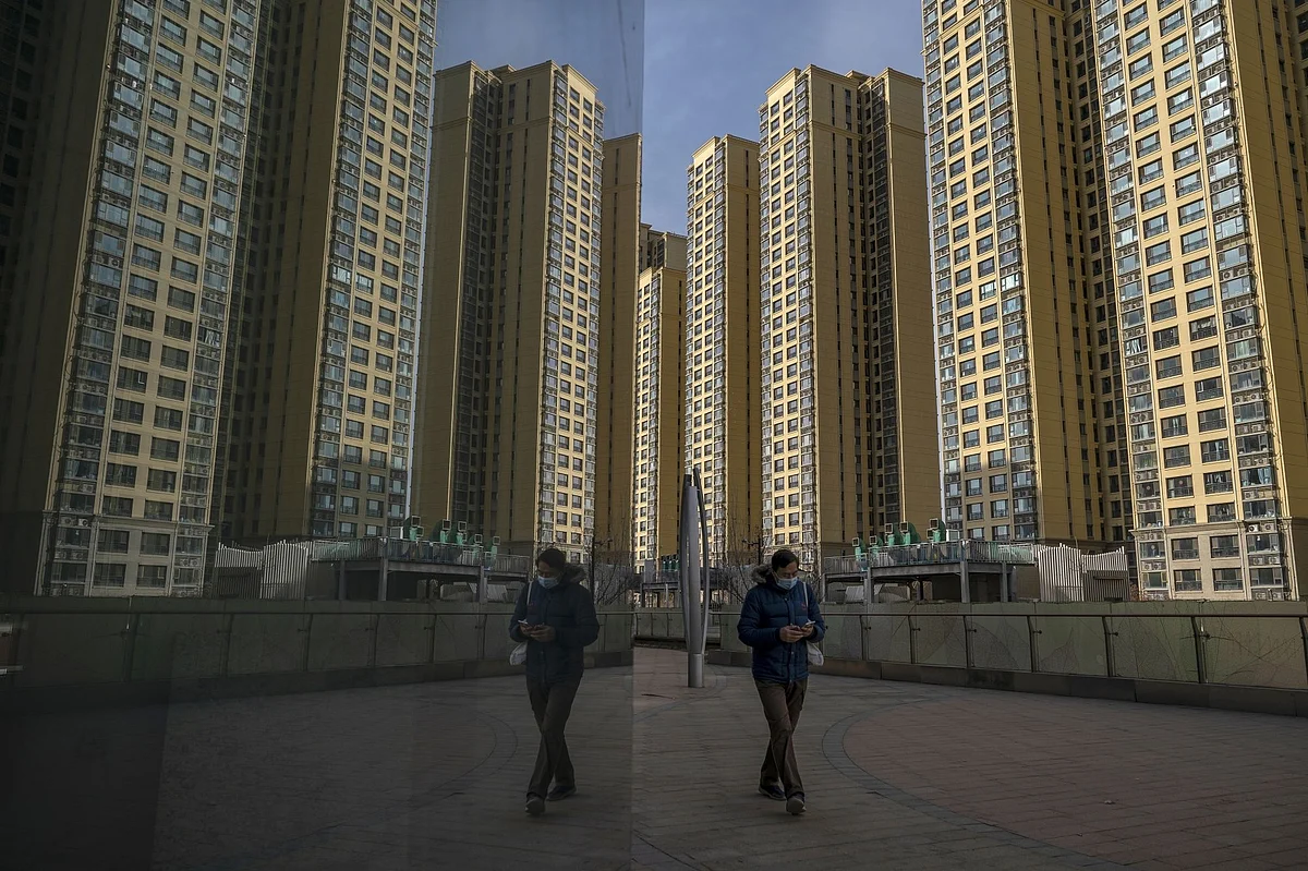 A pedestrian walks past apartment buildings at China Evergrande Group's City Plaza development in Beijing, China, on Friday, Dec. 10, 2021. Evergrande has officially been labeled a defaulter for the first time, the latest milestone in months-long financial drama that’s likely to culminate in a massive restructuring of the world’s most indebted developer.