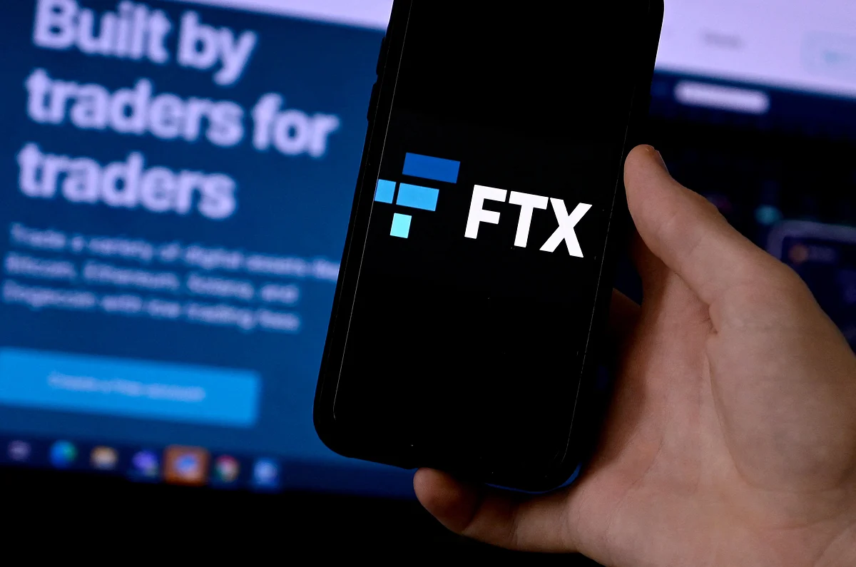 This illustration photo shows a smart phone screen displaying the logo of FTX, the crypto exchange platform, with a screen showing the FTX website in the background in Arlington, Virginia on February 10, 2022. Photographer: Olivier Douliery/AFP/Getty Images