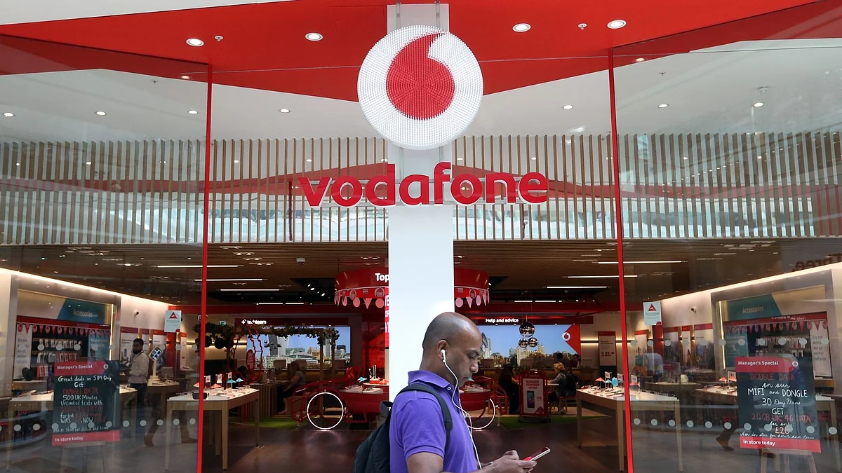 A pedestrian checks his smartphone as he passes the entrance to a Vodafone Group Plc retail store in London, U.K., on Friday, July 22, 2016. Vodafone reported first-quarter service revenue that beat analysts estimates amid gradual improvements in its European mobile-phone businesses and growth in developing markets.