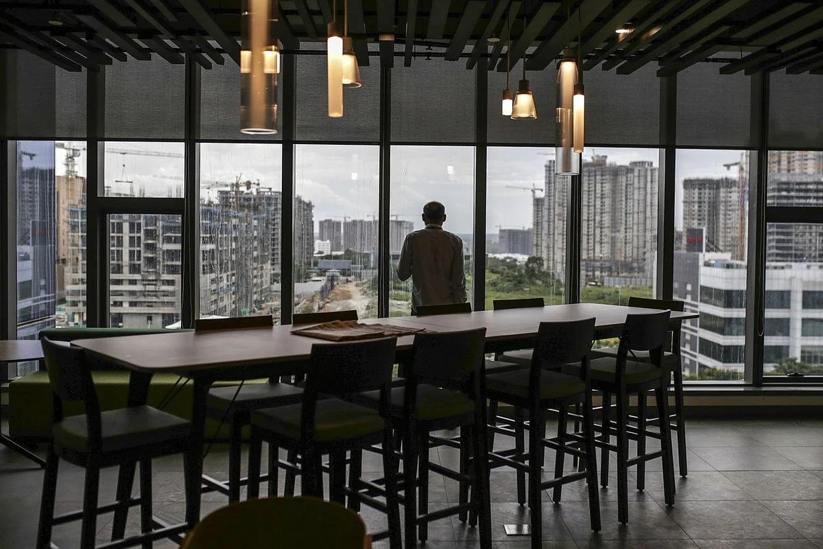 An employee standing at the window looks out over construction sites from the Amazon.com Inc. office campus in Hyderabad , India, on Friday, Sept. 6, 2019. Amazon's only company-owned campus outside the U.S. opened at the end of August on the other side of the globe, thousands of miles from their Seattle headquarters. The 15-storey building towers over the landscape in Hyderabad's technology and financial district, signaling the giant online retailer's ambitions to expand in one of the world's fastest-growing retail markets. Photographer: Dhiraj Singh/Bloomberg