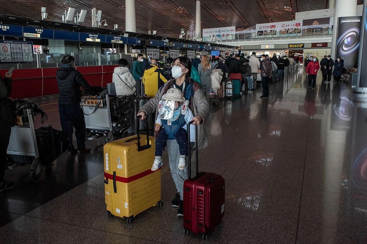 A woman pushes luggage near a check-in counter at Beijing Capital International Airport in Beijing, China, on Friday, Dec. 30, 2022. China could see as many as 25,000 deaths a day from Covid-19 later in January, casting a shadow over the start of the first Lunar New Year festivities without pandemic restrictions. Bloomberg