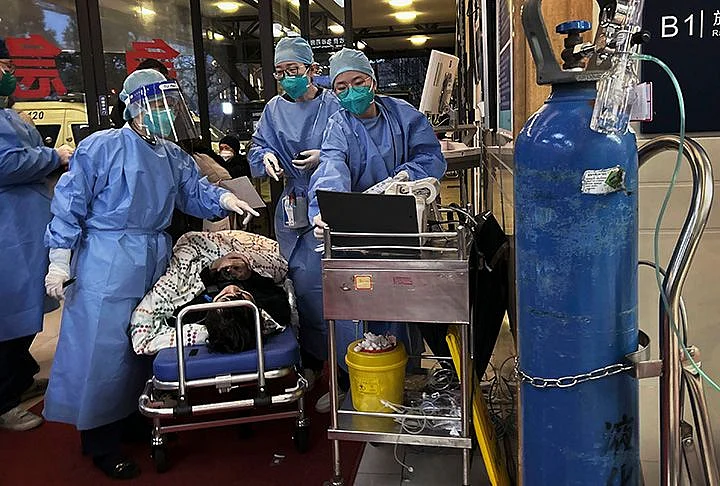 SHANGHAI, CHINA - JANUARY 14: (CHINA AND HONG KONG-OUT) Medical staff triage a patient after being brought by ambulance at the entrance of a busy hospital on January 14, 2023 in Shanghai, China.Chinas health care system has been struggling to cope with a surge of COVID-19 infections since the government ended nearly three years of tough zero COVID controls. At least 900 million people have been infected, according to a Peking University study, and authorities have reported 60,000 COVID-related deaths in hospitals alone in the past month. Infections have peaked in major cities including Beijing and Shanghai, but a second wave is expected to hit in rural areas with hundreds of millions of people traveling to their hometowns during the Lunar New Year holiday. Health officials are concerned that rural populations tend to be older, and the medical system in smaller towns and villages are not as well-resourced as bigger cities. (Photo by Kevin Frayer/Getty Images)