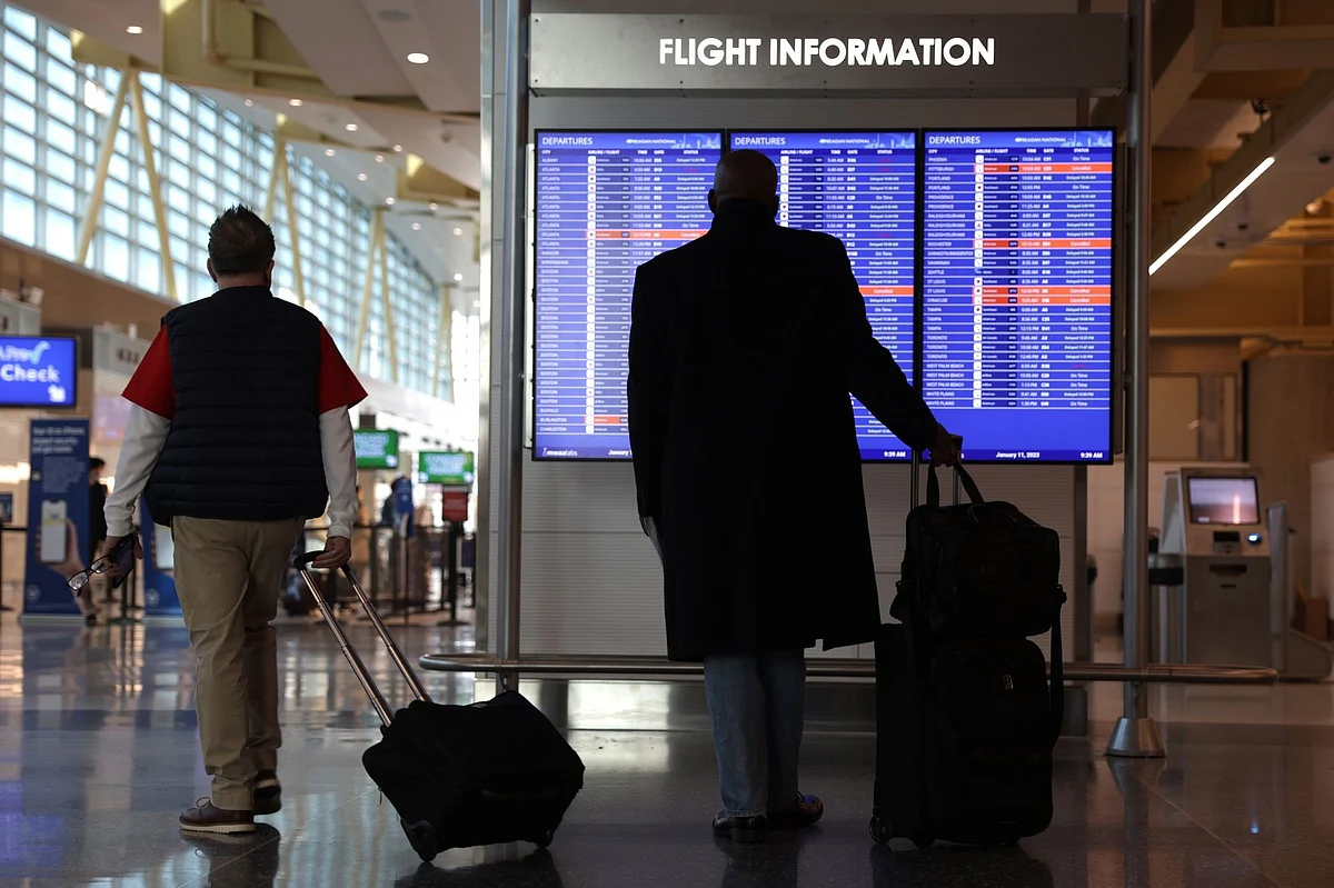 ARLINGTON, VIRGINIA - JANUARY 11: Travelers look at a flight information board at Ronald Reagan Washington National Airport on January 11, 2023 in Arlington, Virginia. The FAA said it is gradually resuming flights around the country after an outage to the Notice to Air Mission System, a computer system that helps guide air traffic. (Photo by Alex Wong/Getty Images)