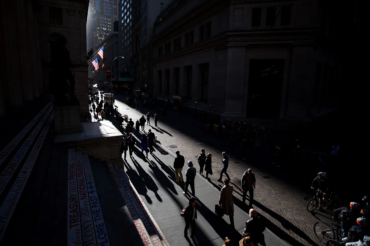 Pedestrians walk along Wall Street. Photographer: Michael Nagle/Bloomberg