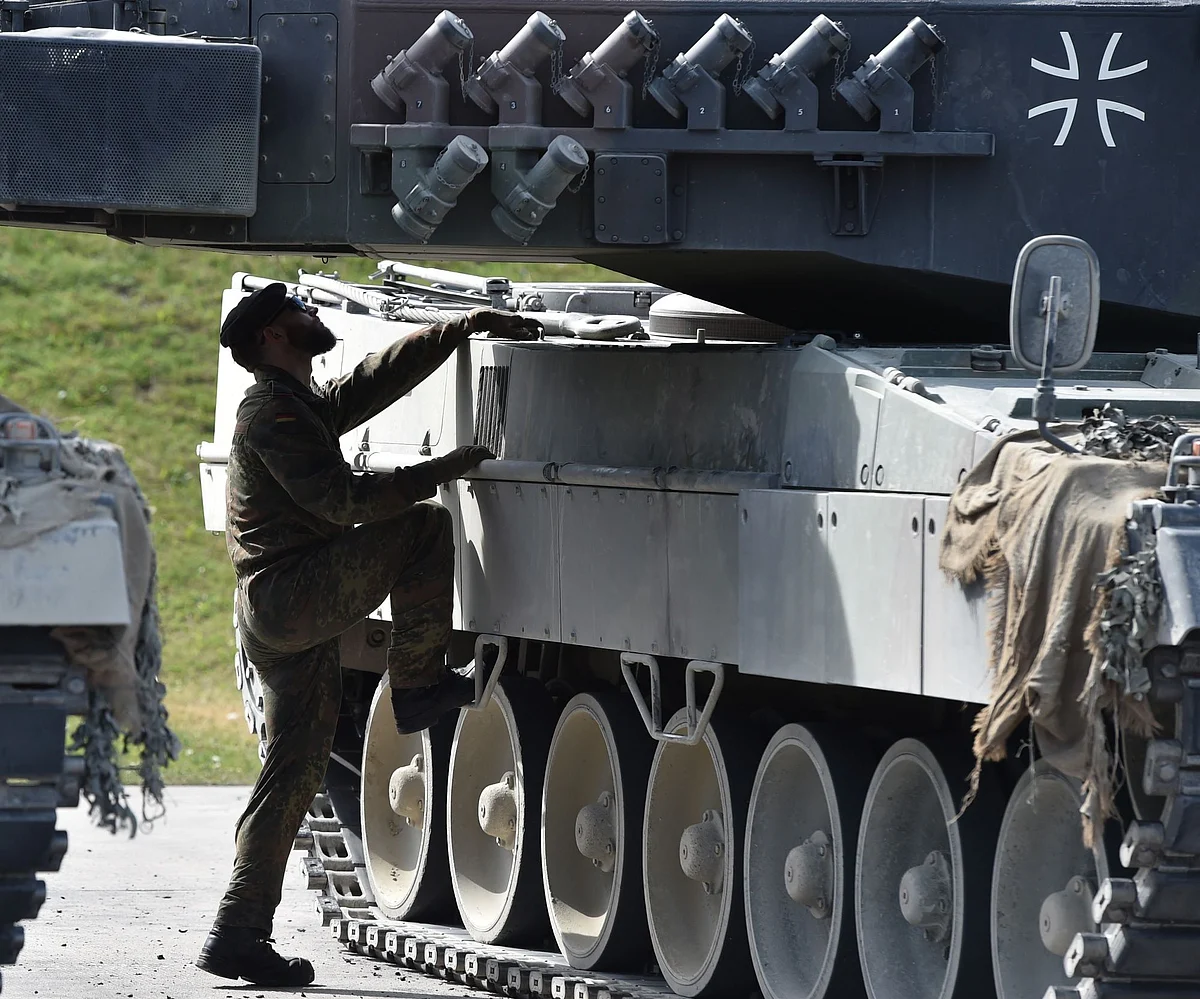 A soldier climbs on to a Leopard battle tank during military exercises in Germany. Photographer: Christof Stache/AFP/Getty Images