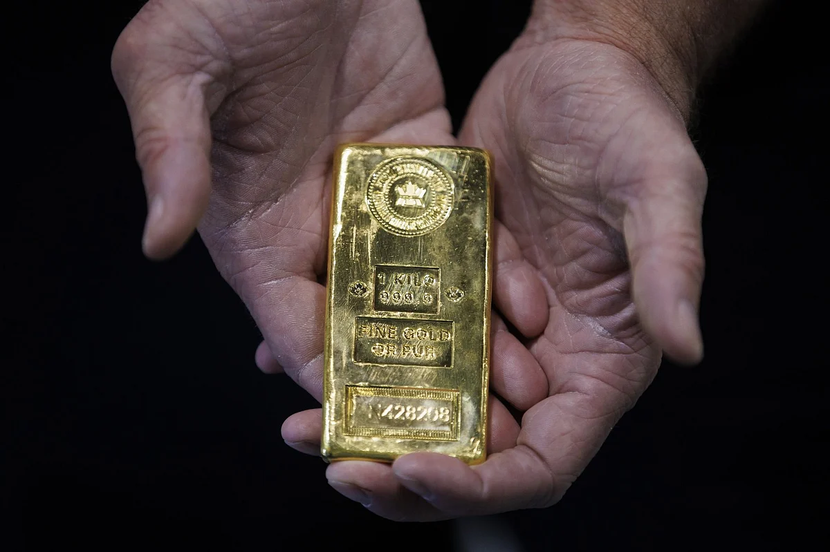 An exhibitor holds a 1 kilo bar of gold at the Prospectors & Developers Association of Canada (PDAC) conference in Toronto. Photographer: Cole Burston/Bloomberg