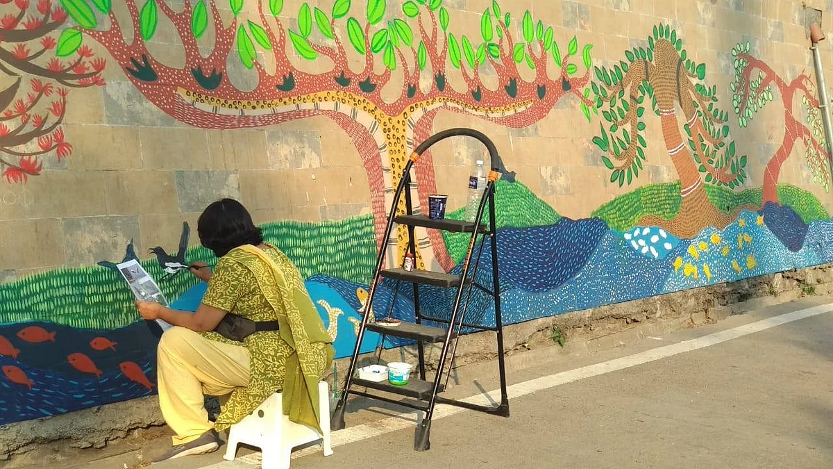 Abha lending finishing touches to the wall painting mural by the people