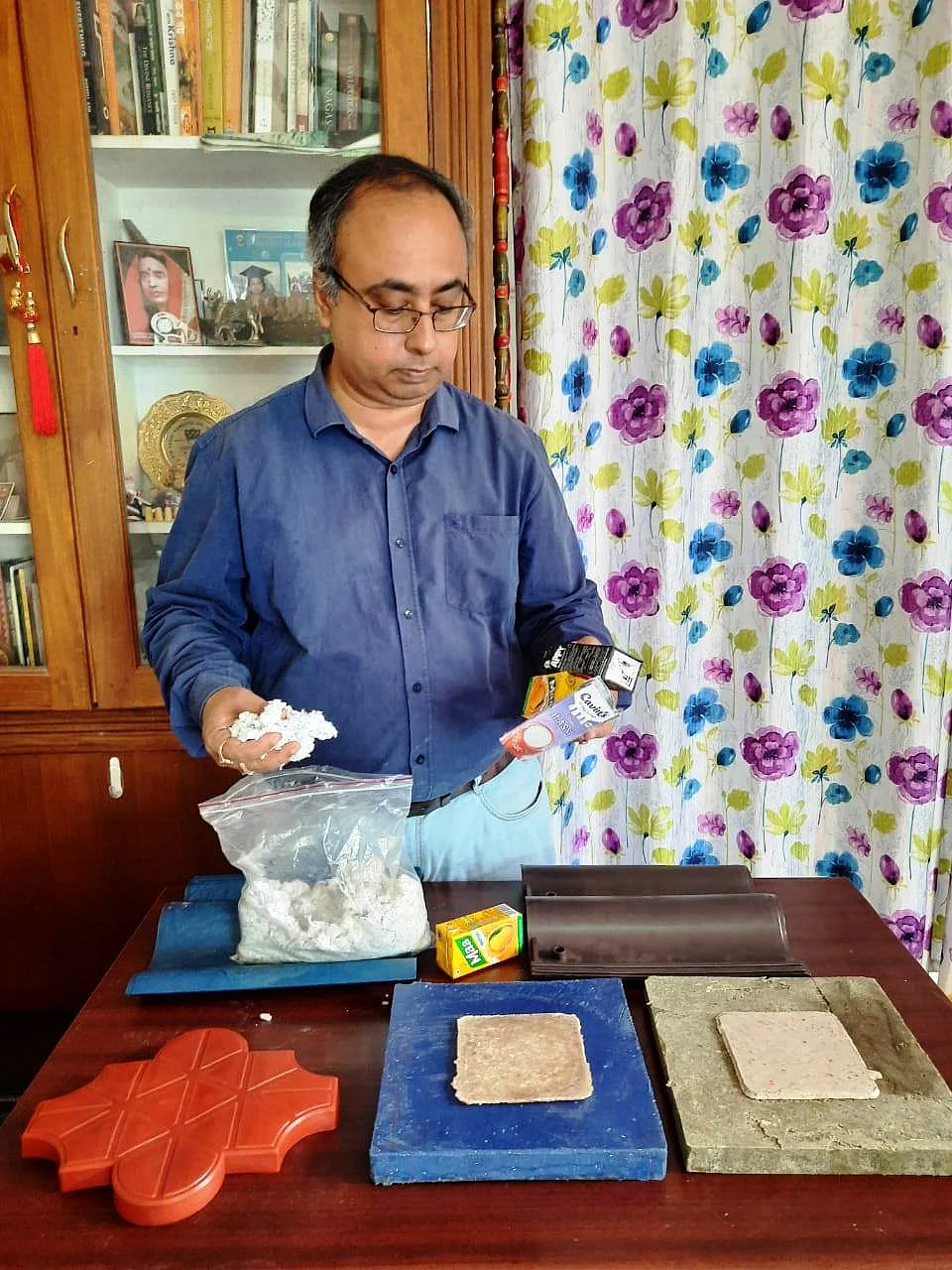 Dr Bhowmik with the roof tiles, paver blocks and upholstery wool all made from waste material