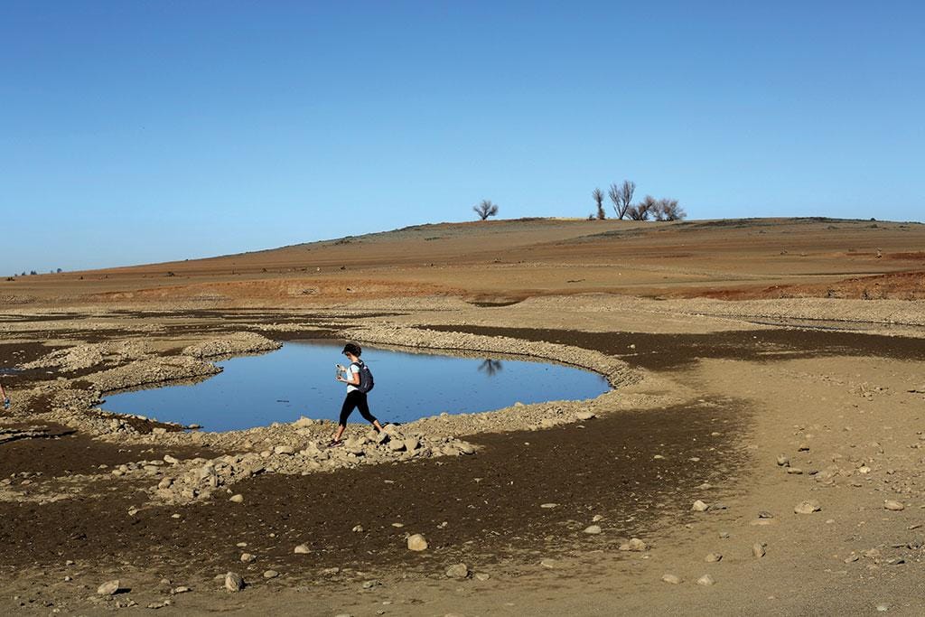 Women carrying water containers in a drought-affected urban area, illustrating the global water scarcity crisis