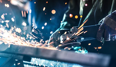 People grinding steel at a hardware workshop with sparks flying